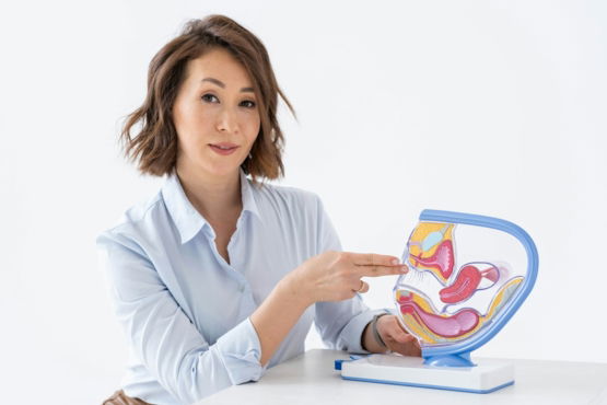 a woman sitting at a table holding a model of a stomach